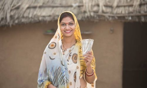 Successful woman holding Indian rupee notes and screaming at village